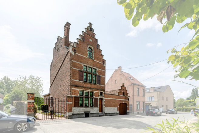Deze karaktervolle burgerwoning in Vlaamse neotraditionele stijl, met haar statige trapgevel en authentieke elementen, ligt op een royaal perceel van 860 m² in het landelijke Beigem (Grimbergen).

Op het gelijkvloers bevindt zich de inkomhal die toegang 