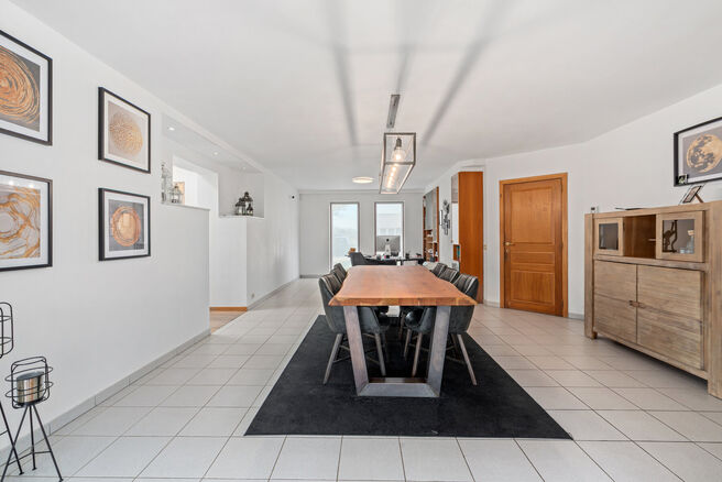 Deze ruime villa met maar liefst 5 slaapkamers en 3 badkamers is gelegen in een residenti&euml;le woonwijk, op een perceel van 15a85ca.

Bij het betreden van de woning komt men in de inkomhal met apart gastentoilet. In 2002 werd de woning uitgebreid met een a