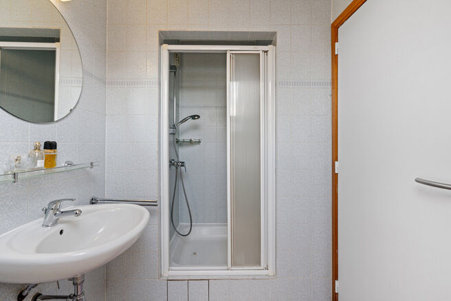 Deze ruime villa met maar liefst 5 slaapkamers en 3 badkamers is gelegen in een residenti&euml;le woonwijk, op een perceel van 15a85ca.

Bij het betreden van de woning komt men in de inkomhal met apart gastentoilet. In 2002 werd de woning uitgebreid met een a