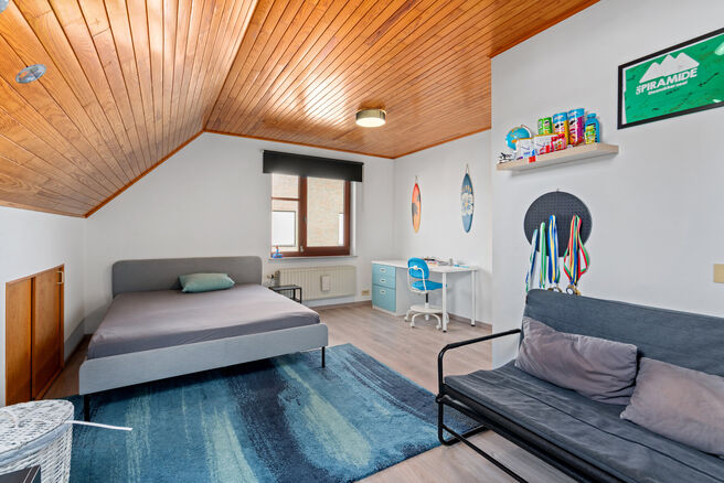Deze ruime villa met maar liefst 5 slaapkamers en 3 badkamers is gelegen in een residenti&euml;le woonwijk, op een perceel van 15a85ca.

Bij het betreden van de woning komt men in de inkomhal met apart gastentoilet. In 2002 werd de woning uitgebreid met een a