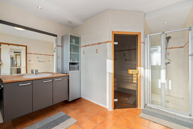 Cette spacieuse villa comprenant pas moins de 5 chambres et 3 salles de bains est situ&eacute;e dans un quartier r&eacute;sidentiel, sur un terrain de 15a85ca.

En entrant dans la maison, vous acc&eacute;dez au hall d&rsquo;entr&eacute;e avec un WC invit&eacute;s s&eacute;par&eacute;. En 2002, la pro