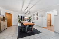 Deze ruime villa met maar liefst 5 slaapkamers en 3 badkamers is gelegen in een residenti&euml;le woonwijk, op een perceel van 15a85ca.

Bij het betreden van de woning komt men in de inkomhal met apart gastentoilet. In 2002 werd de woning uitgebreid met een a