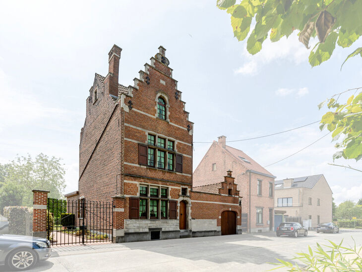 Deze karaktervolle burgerwoning in Vlaamse neotraditionele stijl, met haar statige trapgevel en authentieke elementen, ligt op een royaal perceel van 860 m² in het landelijke Beigem (Grimbergen).

Op het gelijkvloers bevindt zich de inkomhal die toegang 